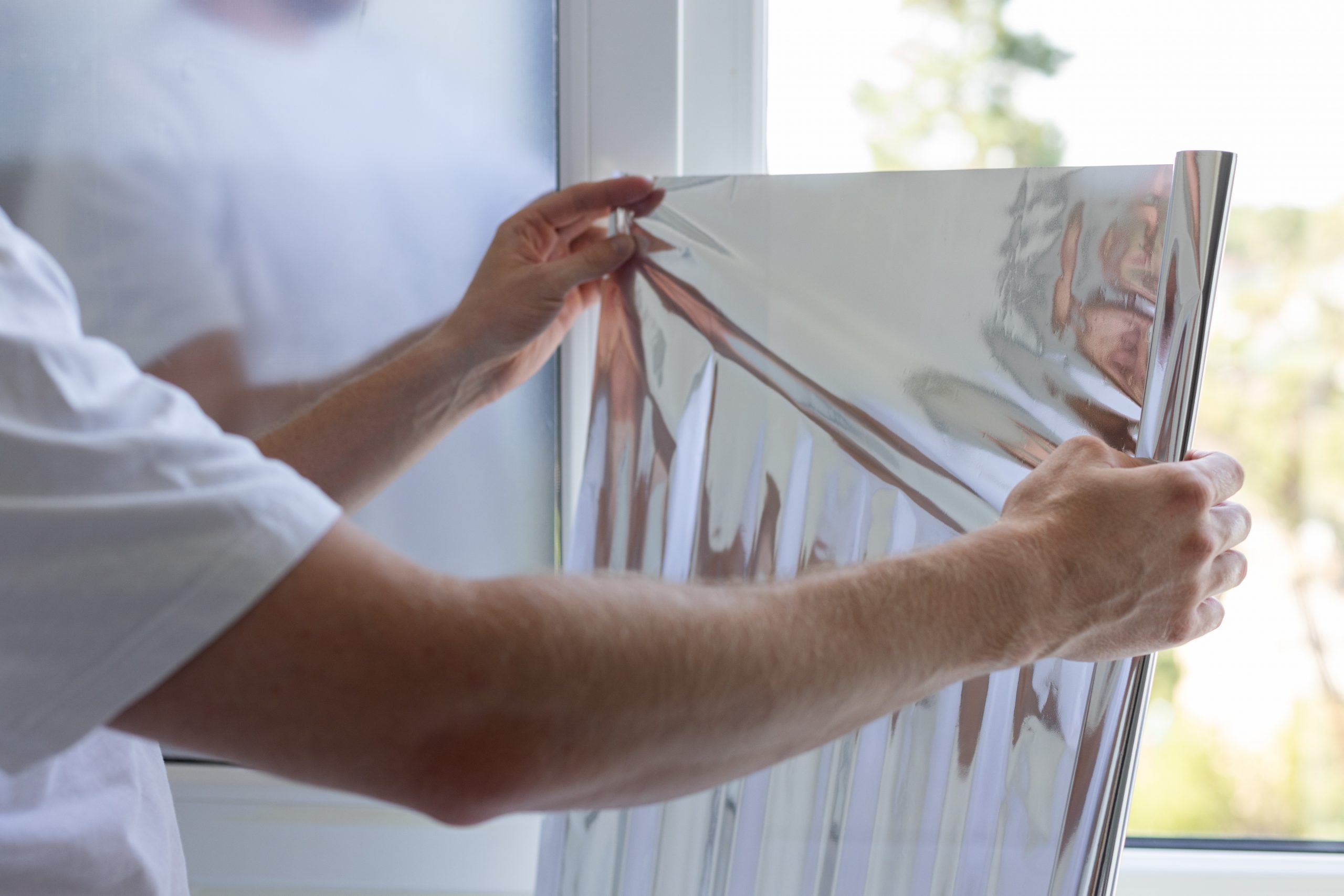 Man holding unrolled windows sun protection film. Closeup. Rénovation, entretien & réparation toiture mobil home